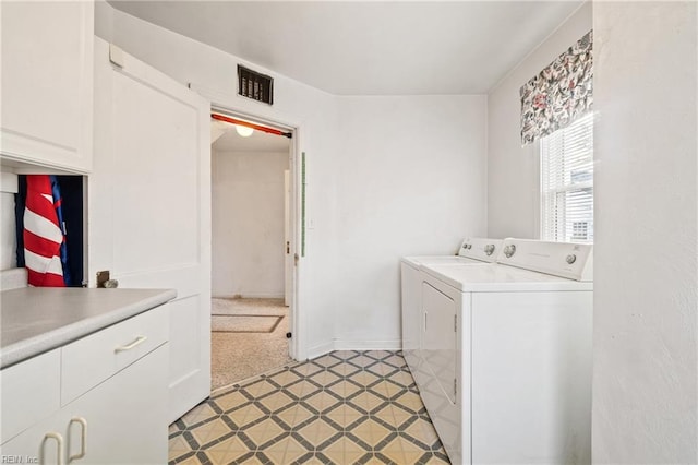 clothes washing area featuring washing machine and dryer, light colored carpet, and cabinets