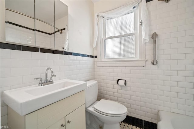 bathroom featuring vanity, toilet, and tile walls