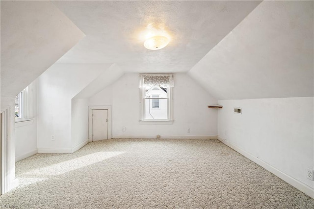 additional living space featuring a wealth of natural light, light carpet, and vaulted ceiling