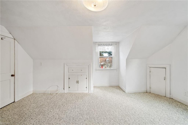 bonus room with light colored carpet and vaulted ceiling