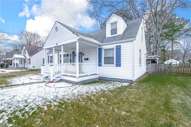 new england style home featuring a porch and a yard