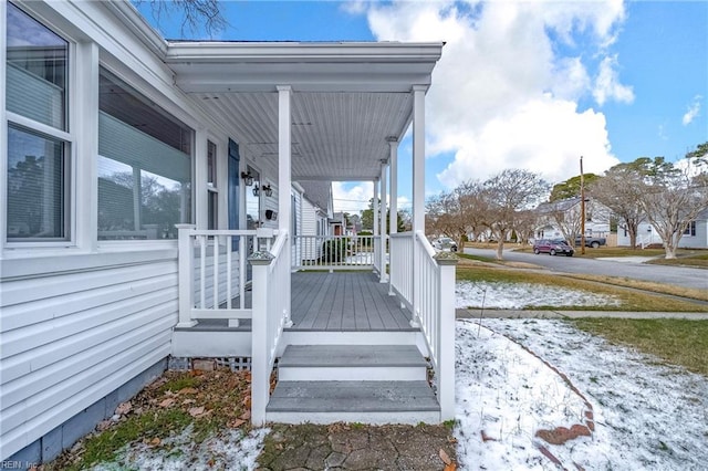 snow covered deck featuring covered porch