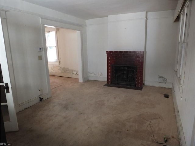 unfurnished living room featuring light colored carpet and a brick fireplace