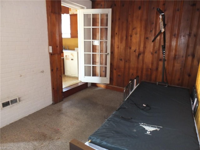 interior space with carpet floors, wooden walls, and brick wall