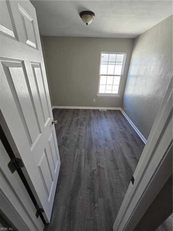 unfurnished room with baseboards and dark wood finished floors