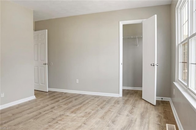 unfurnished bedroom with light wood-style floors, baseboards, visible vents, and a closet