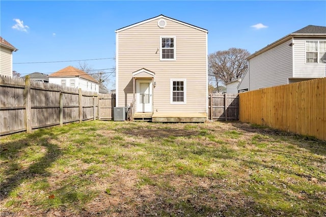 back of property with entry steps, a fenced backyard, a lawn, and central air condition unit