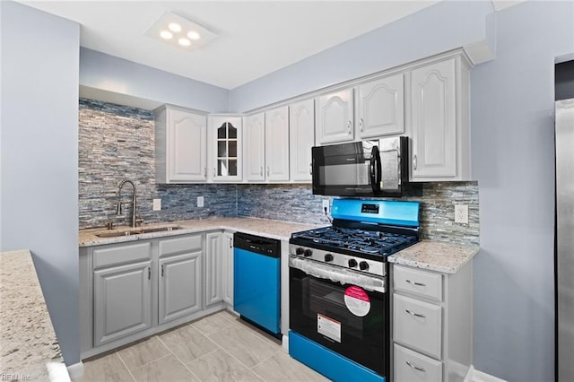 kitchen with light stone countertops, white cabinetry, stainless steel appliances, tasteful backsplash, and sink