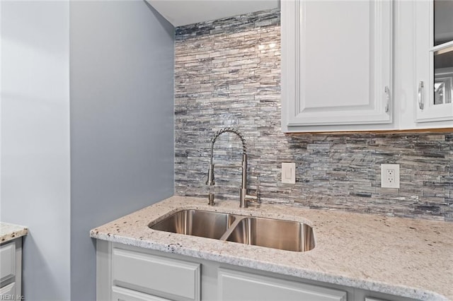 kitchen featuring backsplash, white cabinets, light stone counters, and sink