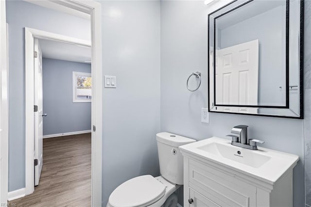 bathroom featuring wood-type flooring, toilet, and vanity