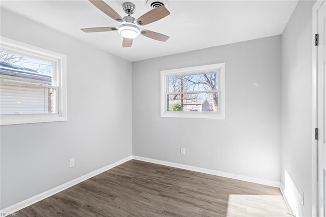 empty room featuring ceiling fan, dark wood-type flooring, and a wealth of natural light