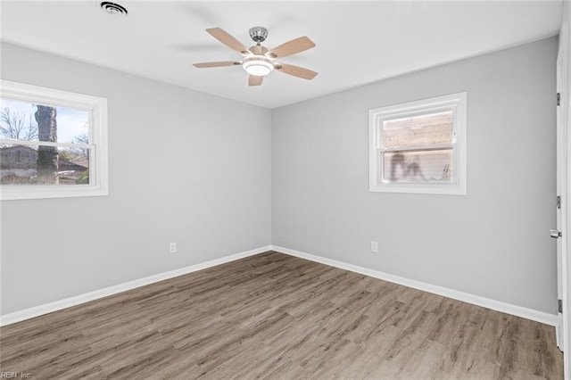 spare room with ceiling fan, a healthy amount of sunlight, and hardwood / wood-style floors