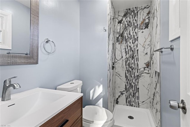 bathroom with toilet, vanity, and a tile shower