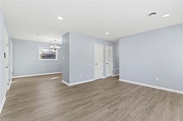 empty room featuring a chandelier and hardwood / wood-style flooring