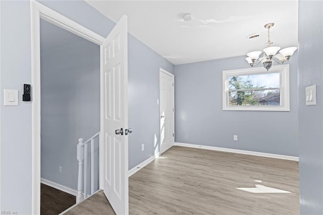 empty room with a notable chandelier and hardwood / wood-style flooring