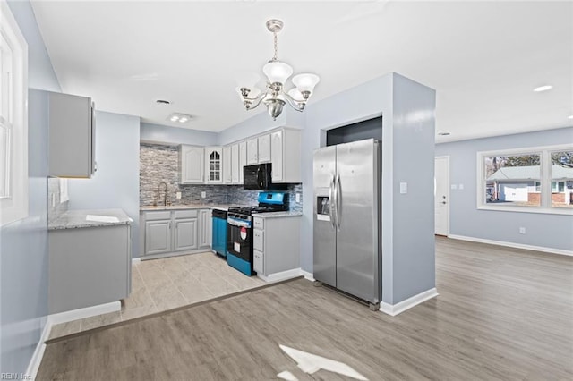 kitchen featuring gray cabinets, pendant lighting, an inviting chandelier, light hardwood / wood-style flooring, and appliances with stainless steel finishes