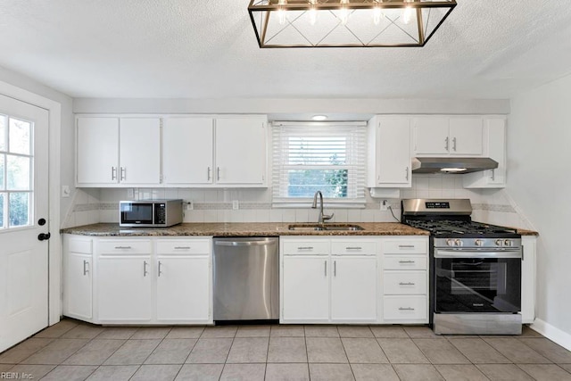 kitchen with white cabinetry, sink, dark stone countertops, light tile patterned flooring, and appliances with stainless steel finishes