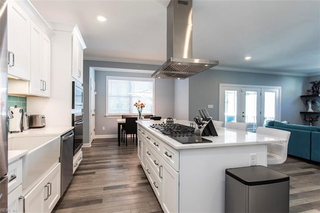 kitchen with island exhaust hood, stainless steel appliances, a healthy amount of sunlight, white cabinets, and a center island