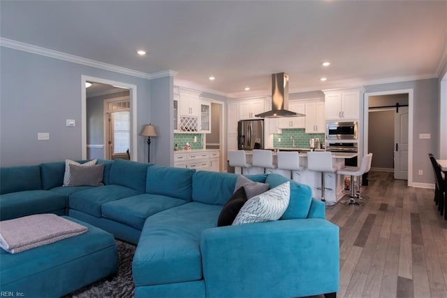 living room with a barn door, light hardwood / wood-style floors, and crown molding