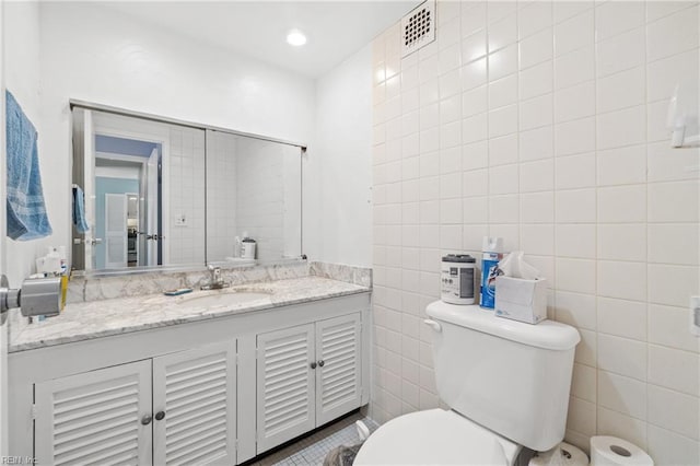 bathroom featuring tile walls, toilet, and vanity