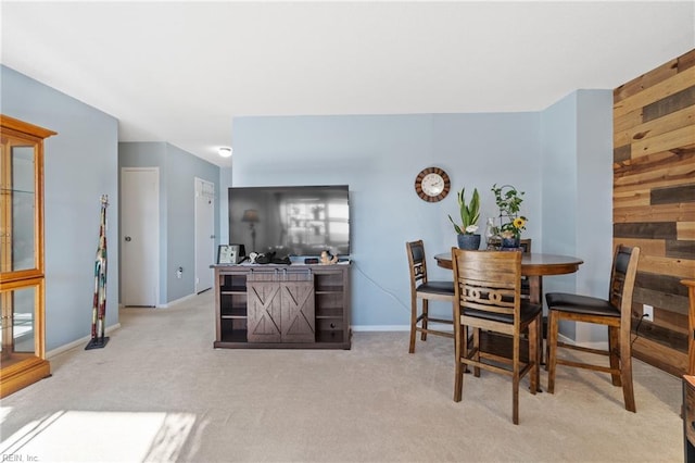 dining area with wooden walls and light colored carpet