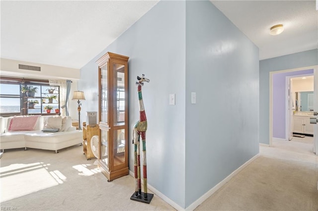 hallway featuring lofted ceiling and light colored carpet