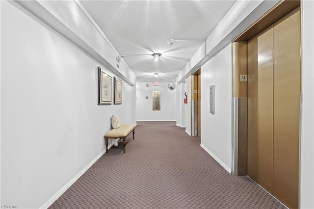 corridor with a textured ceiling, elevator, and dark carpet