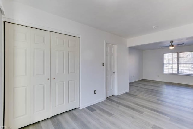 unfurnished bedroom featuring ceiling fan, light wood-type flooring, and a closet