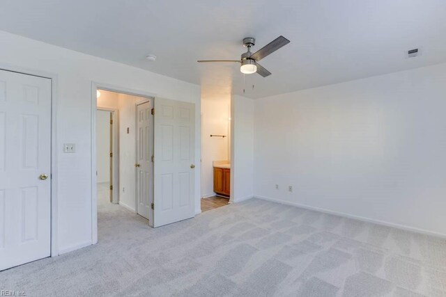 unfurnished bedroom featuring ceiling fan, ensuite bath, and light carpet