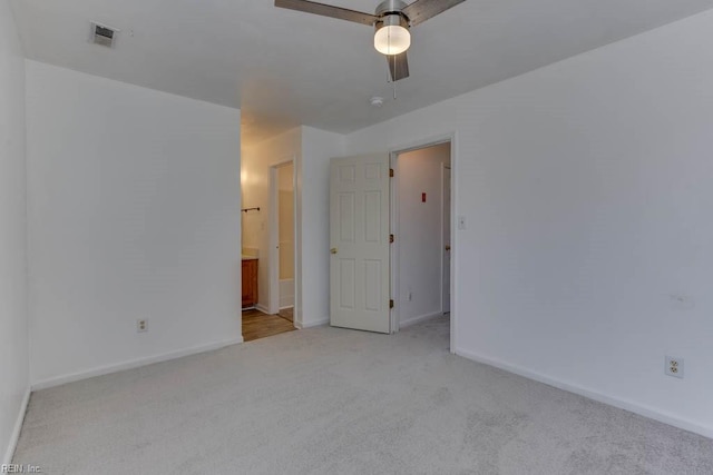 unfurnished bedroom with ensuite bathroom, ceiling fan, and light carpet