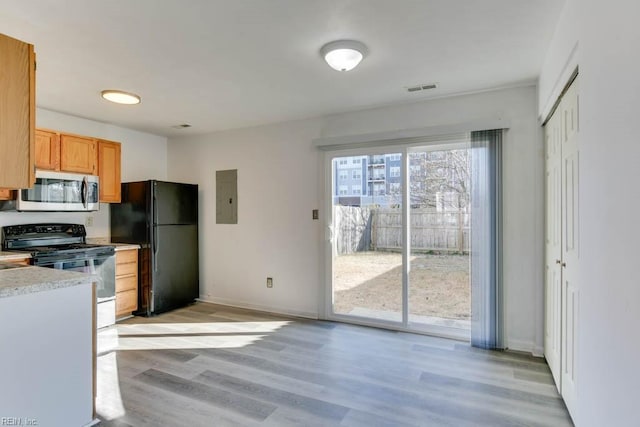 kitchen featuring black appliances, light hardwood / wood-style flooring, light brown cabinets, and electric panel