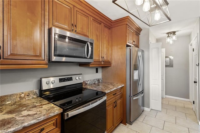 kitchen with light stone countertops, light tile patterned floors, stainless steel appliances, and an inviting chandelier