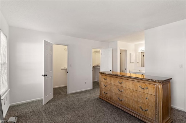 unfurnished bedroom featuring a spacious closet, a closet, and dark colored carpet