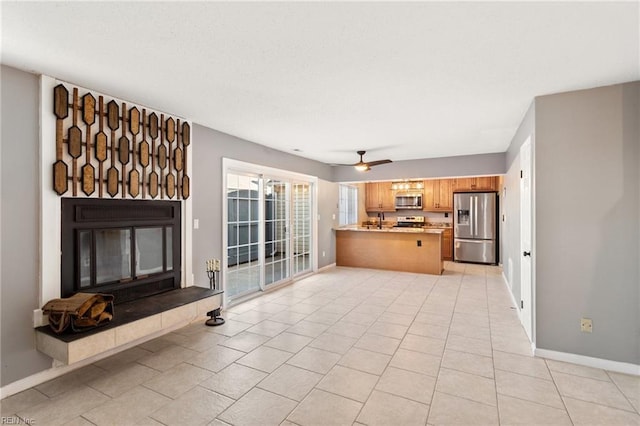 unfurnished living room with ceiling fan, sink, and light tile patterned floors