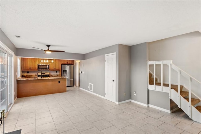 kitchen featuring kitchen peninsula, appliances with stainless steel finishes, a textured ceiling, ceiling fan, and light tile patterned floors