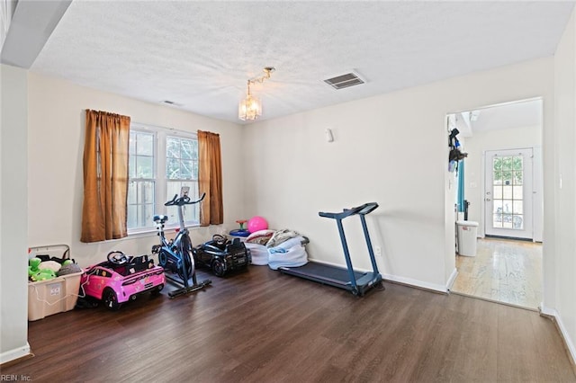 workout area with dark hardwood / wood-style floors, plenty of natural light, and an inviting chandelier