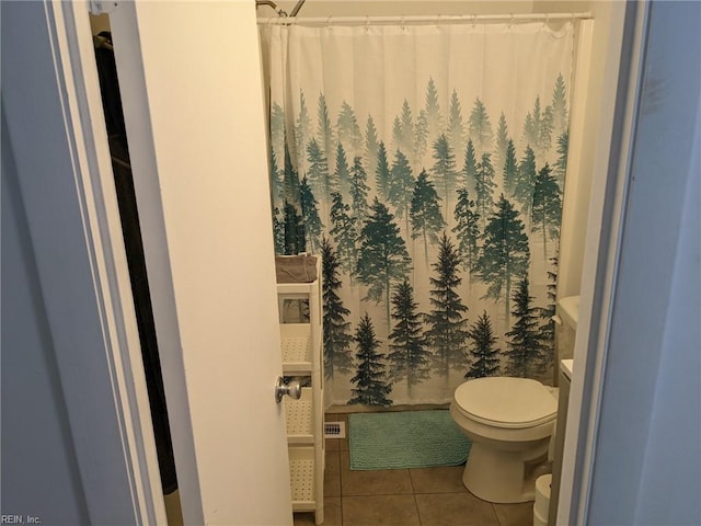 bathroom with toilet, tile patterned flooring, and curtained shower