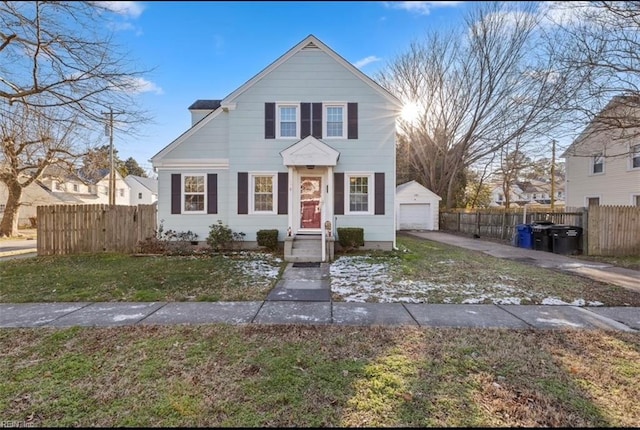 front facade featuring a front yard, a garage, and an outbuilding