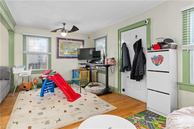 recreation room with a healthy amount of sunlight, ceiling fan, and wood-type flooring