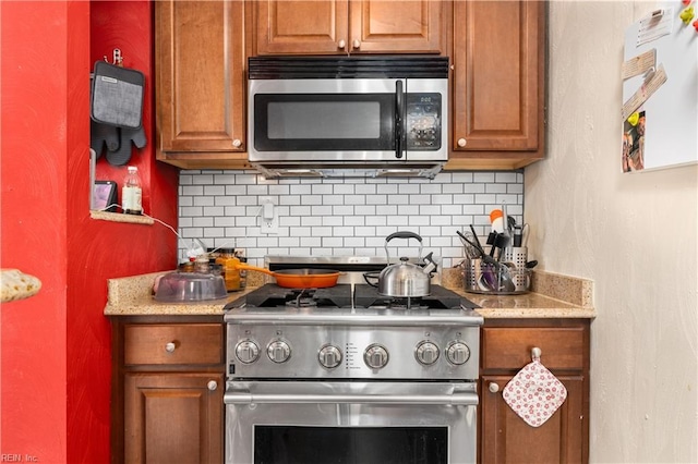 kitchen with stainless steel appliances, backsplash, and light stone countertops