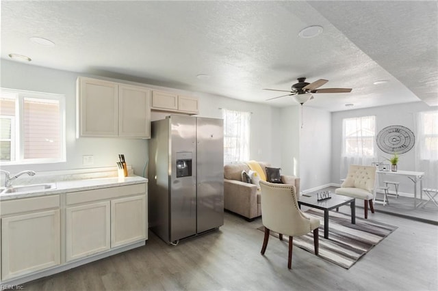 kitchen with plenty of natural light, sink, light hardwood / wood-style floors, and stainless steel refrigerator with ice dispenser