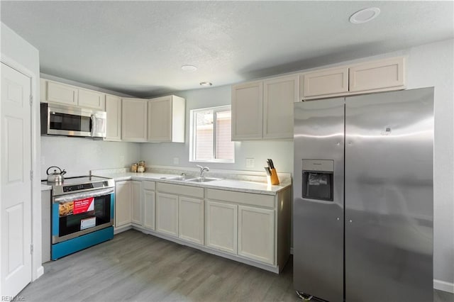 kitchen featuring sink, white cabinetry, stainless steel appliances, and light hardwood / wood-style flooring