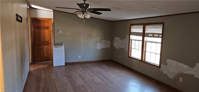 empty room with a textured ceiling, dark hardwood / wood-style flooring, ceiling fan, and ornamental molding