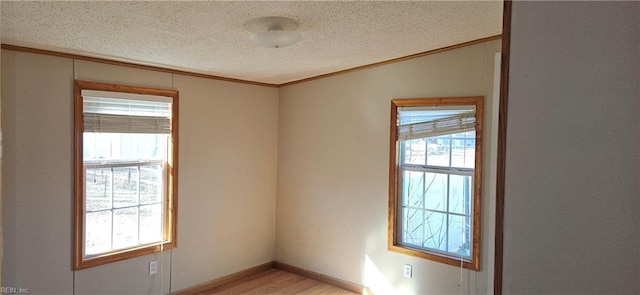 unfurnished room featuring a textured ceiling, light hardwood / wood-style flooring, and crown molding