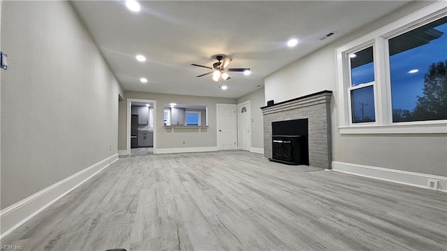 unfurnished living room featuring ceiling fan, a fireplace, and light hardwood / wood-style floors