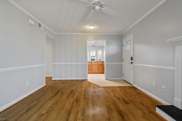 foyer entrance with a textured ceiling, hardwood / wood-style floors, ceiling fan, and ornamental molding