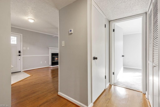 hall featuring ornamental molding, a textured ceiling, and wood-type flooring