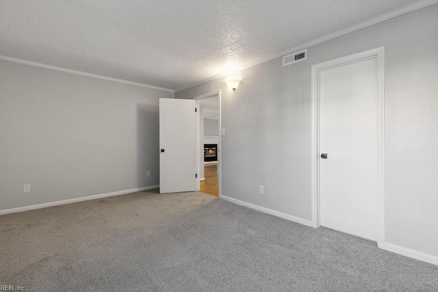 carpeted empty room featuring a textured ceiling and ornamental molding