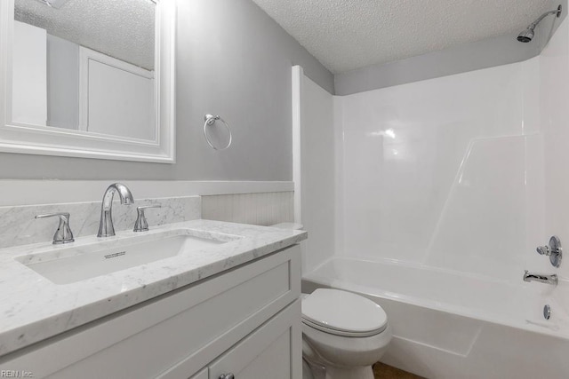 full bathroom with a textured ceiling, tub / shower combination, vanity, and toilet