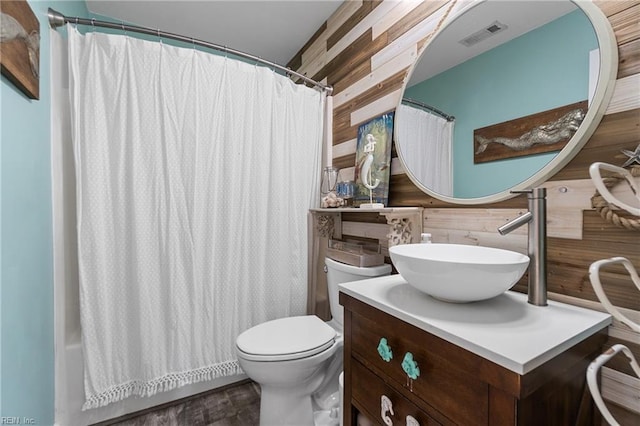 bathroom with toilet, vanity, wood walls, and a shower with shower curtain